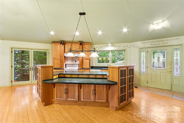 kitchen with white electric range oven, a kitchen bar, light wood-style flooring, and dark countertops