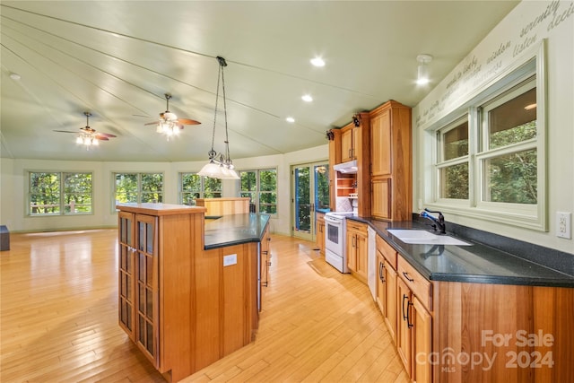 kitchen with brown cabinets, a kitchen island, lofted ceiling, electric stove, and a sink