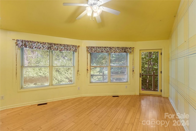 unfurnished room with visible vents, light wood-style floors, a ceiling fan, and plenty of natural light