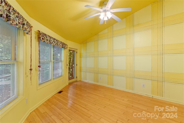 empty room with a ceiling fan, wood finished floors, lofted ceiling, baseboards, and visible vents