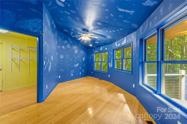 empty room with baseboards, vaulted ceiling, wood finished floors, and a ceiling fan