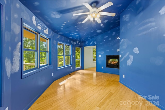 interior space featuring light hardwood / wood-style flooring, ceiling fan, and a multi sided fireplace