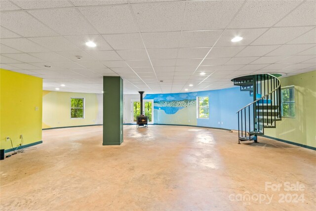 basement featuring a wood stove and a drop ceiling