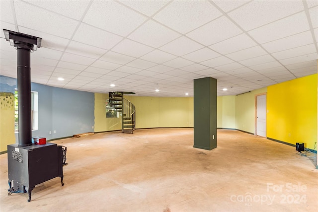 basement with a wood stove and a drop ceiling