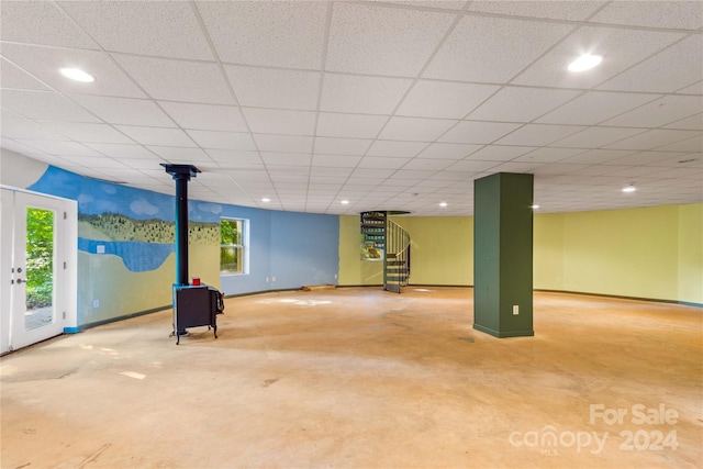 basement featuring baseboards, stairs, recessed lighting, a drop ceiling, and a wood stove