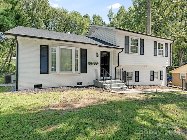 tri-level home with cooling unit and a front lawn