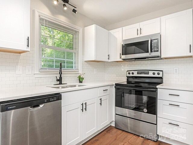 kitchen featuring wood-type flooring, sink, stainless steel appliances, and white cabinets