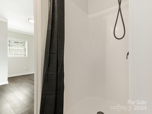 details featuring walk in shower, hardwood / wood-style flooring, and crown molding