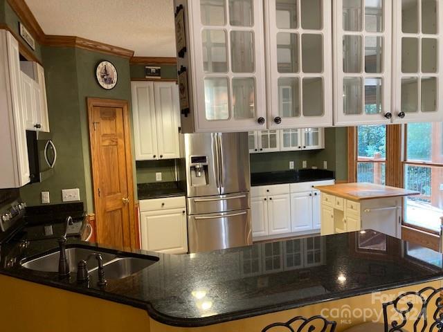 kitchen with a center island, white cabinetry, kitchen peninsula, and stainless steel appliances