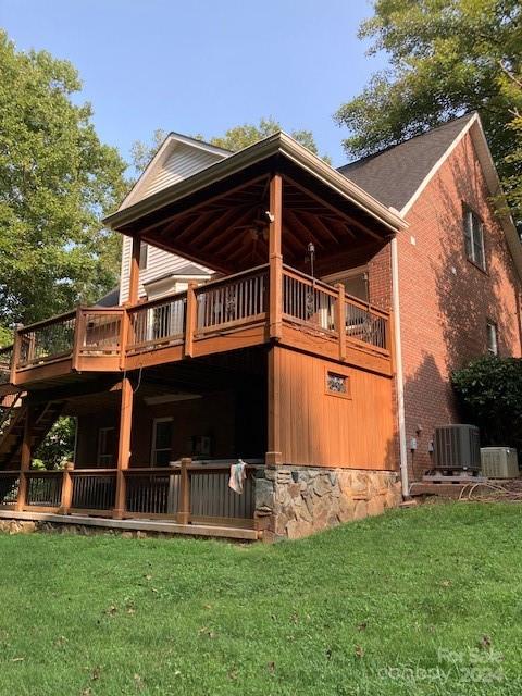 rear view of house featuring cooling unit, a yard, and a deck