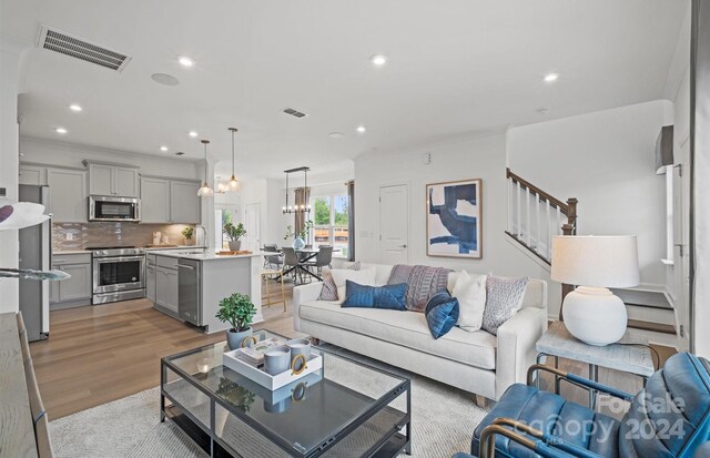 living room with sink, a chandelier, and light hardwood / wood-style flooring