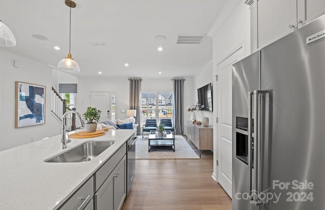 kitchen featuring hardwood / wood-style flooring, light stone countertops, stainless steel appliances, sink, and pendant lighting