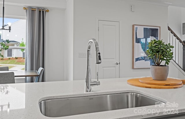 room details with sink, light stone countertops, and a notable chandelier