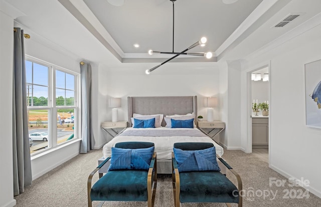 bedroom featuring light colored carpet, connected bathroom, and a raised ceiling