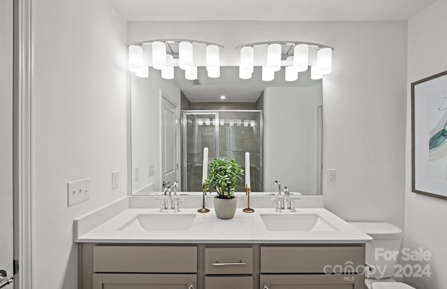 bathroom featuring vanity, toilet, and a shower with door