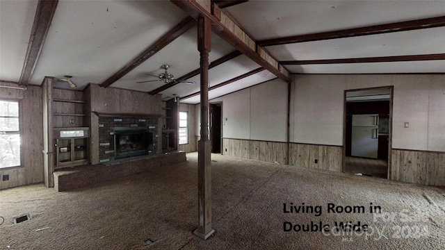 unfurnished living room with wooden walls, vaulted ceiling with beams, ceiling fan, and carpet flooring