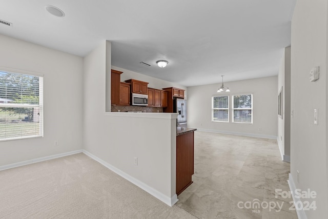 kitchen featuring decorative light fixtures, a notable chandelier, appliances with stainless steel finishes, kitchen peninsula, and decorative backsplash