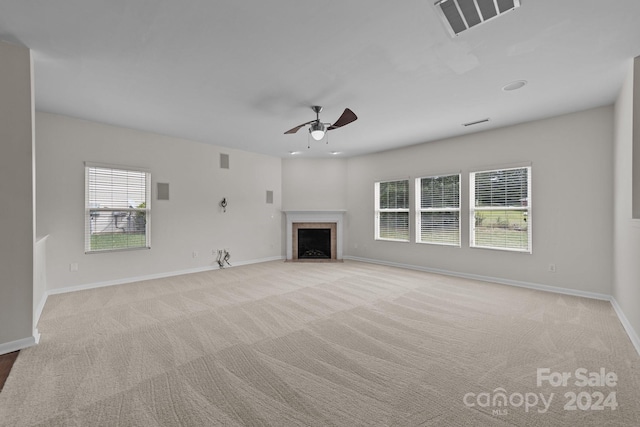 unfurnished living room featuring light colored carpet, plenty of natural light, and ceiling fan