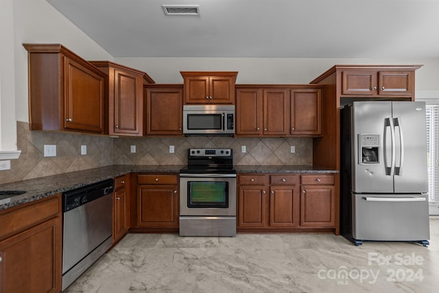 kitchen with dark stone countertops, appliances with stainless steel finishes, and decorative backsplash