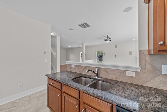 kitchen featuring dark stone counters, backsplash, and sink