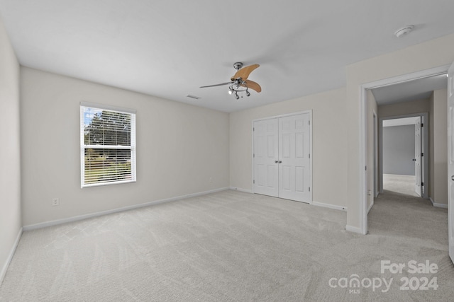 unfurnished bedroom with a closet, ceiling fan, and light carpet