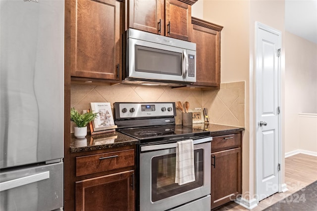 kitchen with dark stone counters, stainless steel appliances, hardwood / wood-style floors, and tasteful backsplash