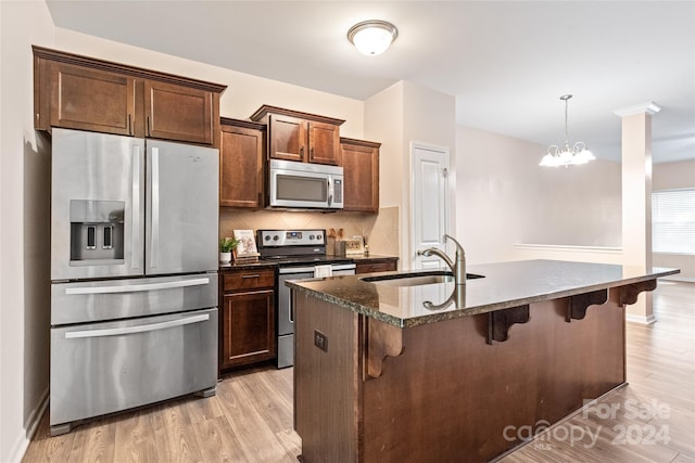 kitchen featuring stainless steel appliances, tasteful backsplash, light wood-type flooring, and sink