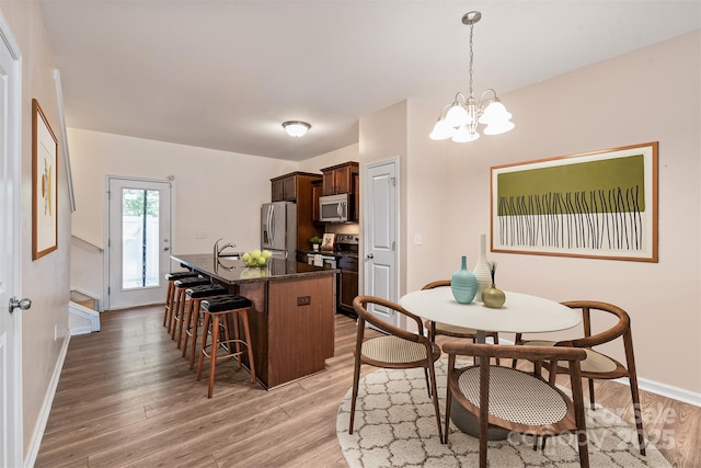 kitchen featuring a breakfast bar, dark brown cabinets, hanging light fixtures, hardwood / wood-style flooring, and stainless steel appliances