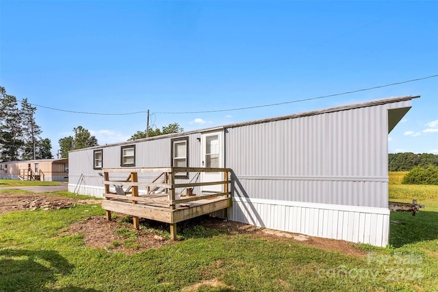 back of property featuring a wooden deck and a lawn