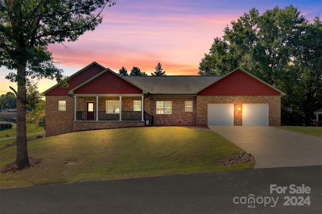 view of front of property featuring a yard, a garage, and a porch