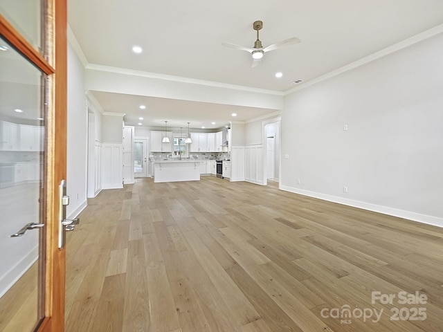 unfurnished living room with ceiling fan, ornamental molding, and light hardwood / wood-style flooring