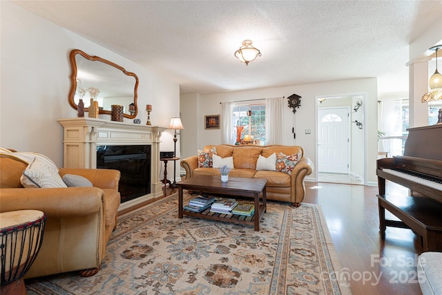 living room with a fireplace, wood-type flooring, and a textured ceiling