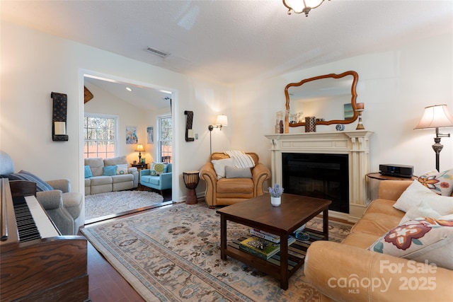 living room with hardwood / wood-style floors, a textured ceiling, and vaulted ceiling