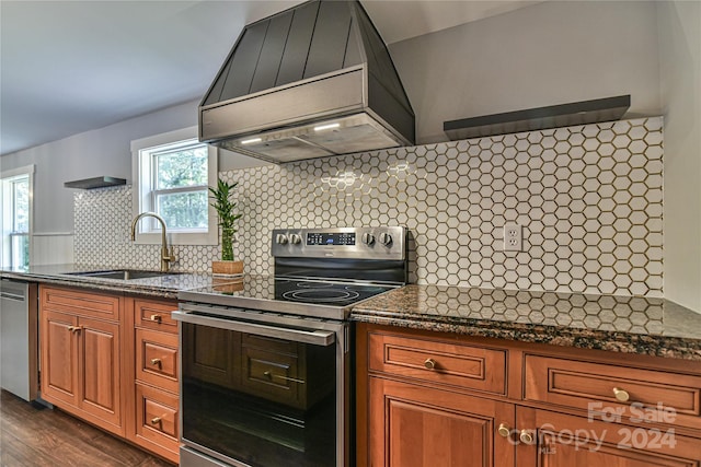 kitchen with tasteful backsplash, stainless steel appliances, premium range hood, sink, and dark wood-type flooring