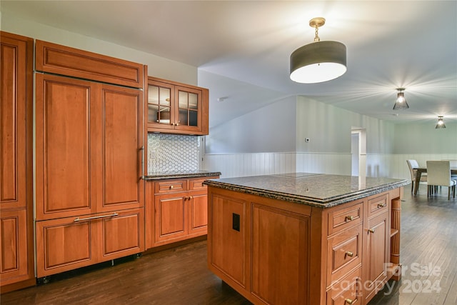 kitchen featuring a center island, tasteful backsplash, dark hardwood / wood-style floors, and dark stone counters