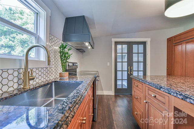 kitchen featuring stainless steel range with electric stovetop, dark stone countertops, sink, dark hardwood / wood-style floors, and wall chimney exhaust hood