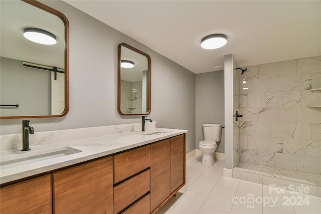 bathroom with tiled shower, vanity, toilet, and tile patterned floors