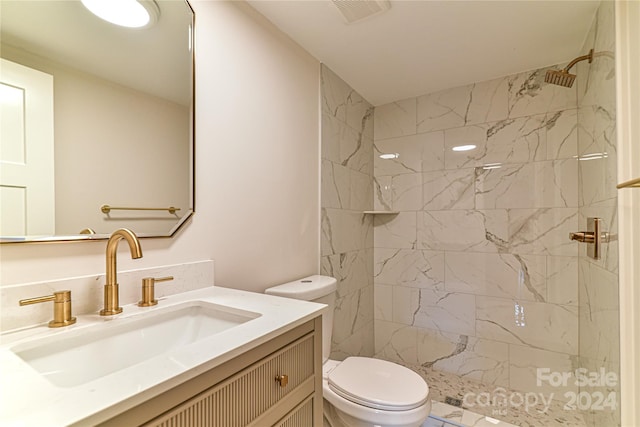 bathroom featuring tiled shower, vanity, and toilet