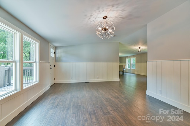 unfurnished room with lofted ceiling, plenty of natural light, dark hardwood / wood-style floors, and an inviting chandelier