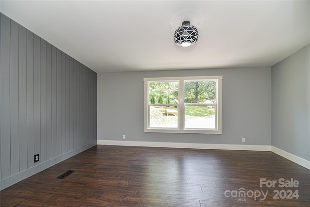 spare room with wooden walls and dark hardwood / wood-style flooring