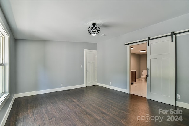 spare room with dark wood-type flooring and a barn door