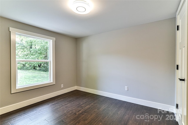 empty room with a healthy amount of sunlight and dark wood-type flooring