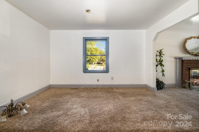 unfurnished room featuring carpet floors and a fireplace