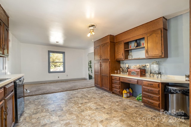 kitchen with built in desk, dishwasher, and light colored carpet