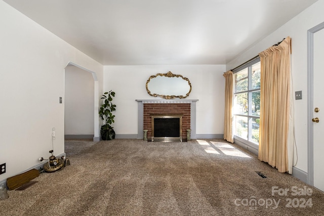 unfurnished living room featuring carpet flooring, a fireplace, and plenty of natural light