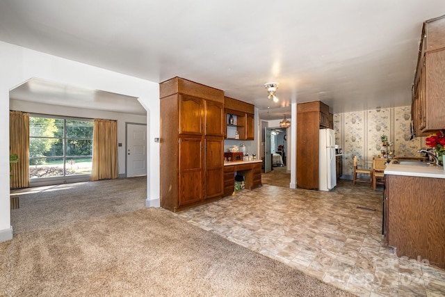 kitchen with light carpet, sink, and white refrigerator