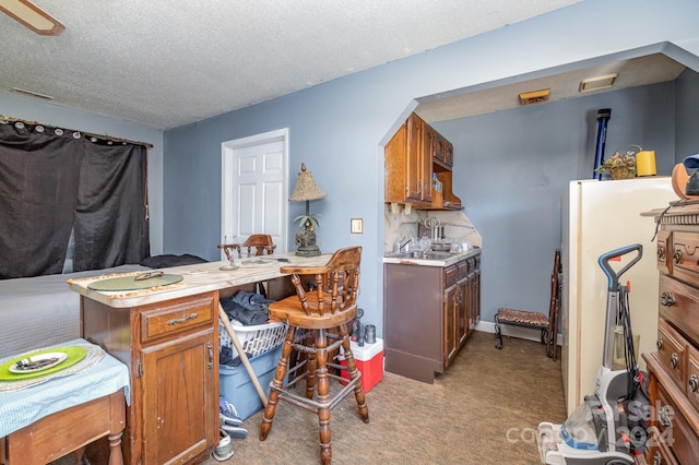 kitchen with light carpet, a textured ceiling, and backsplash