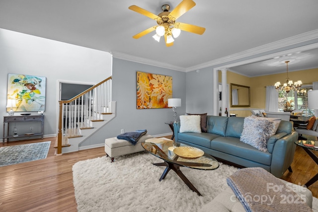 living room with ceiling fan with notable chandelier, decorative columns, ornamental molding, and light hardwood / wood-style flooring