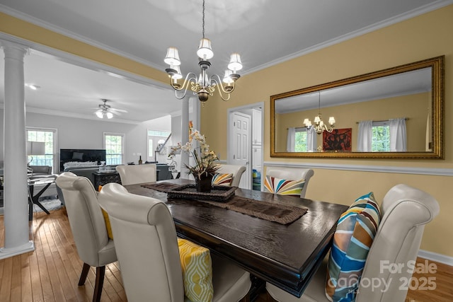 dining space featuring ceiling fan with notable chandelier, crown molding, wood-type flooring, and ornate columns