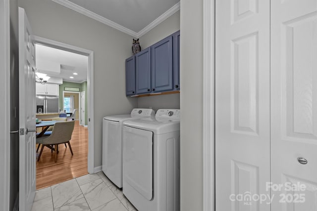 clothes washing area with washer and clothes dryer, crown molding, and cabinets